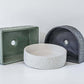 Four geometric and textured concrete basins, including circular, rectangular, and semi-circular shapes, are displayed against a simple white background. Each basin has distinct patterns and surface details.