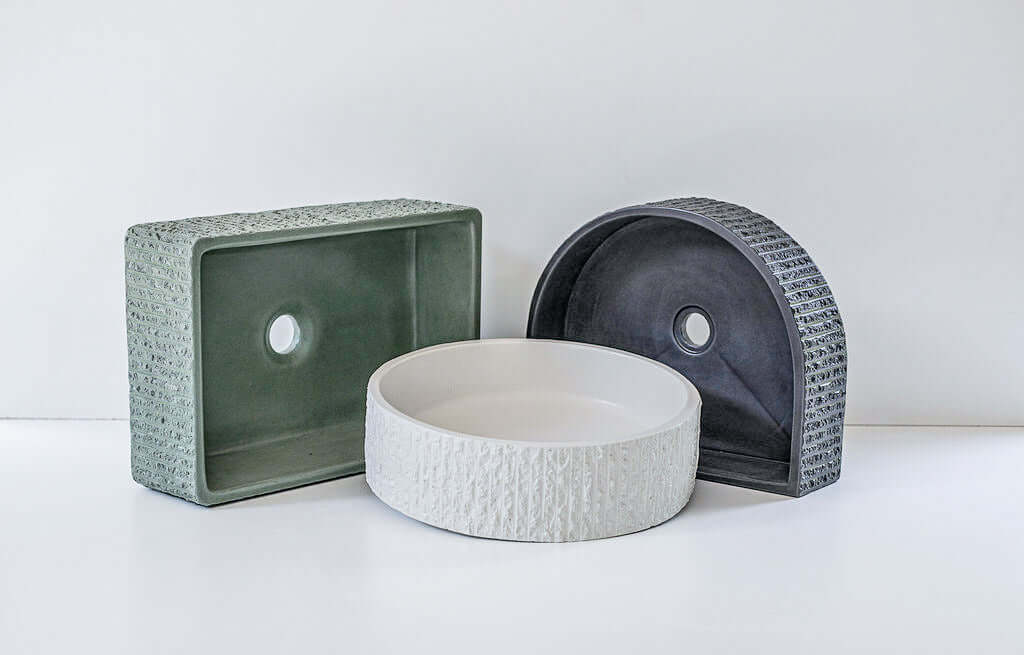 Four geometric and textured concrete basins, including circular, rectangular, and semi-circular shapes, are displayed against a simple white background. Each basin has distinct patterns and surface details.