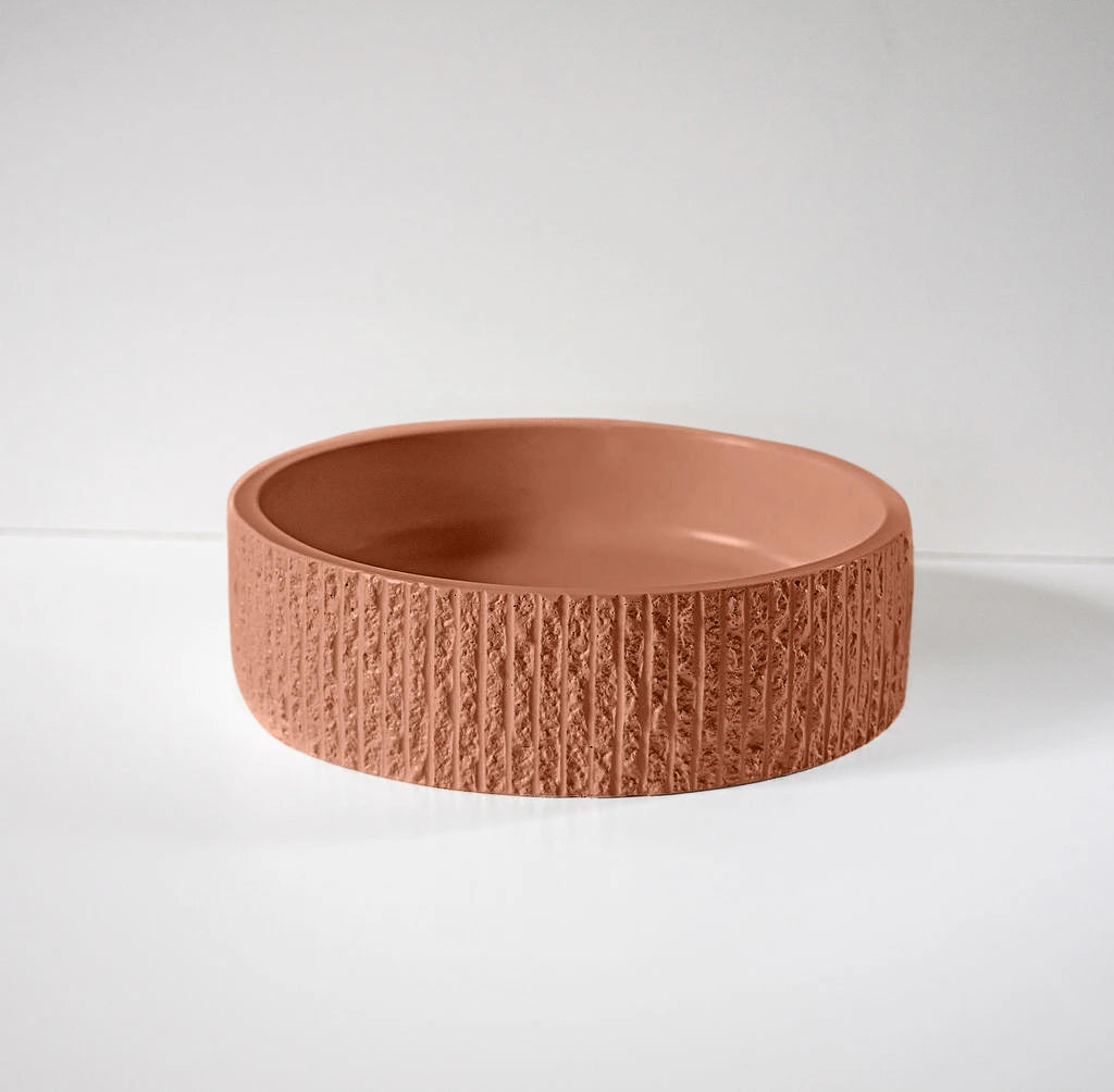 A textured, terracotta-colored round bowl rests on a smooth, white surface against a plain backdrop.