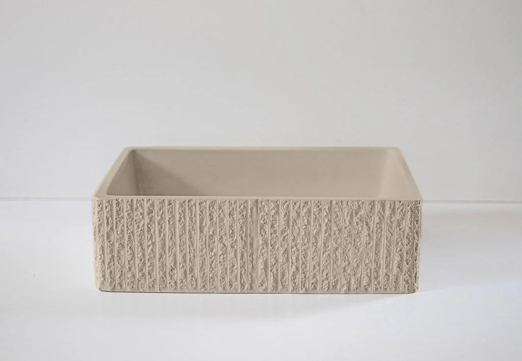 A beige rectangular basin with a textured, grooved exterior surface is placed centrally against a plain, light-colored background.