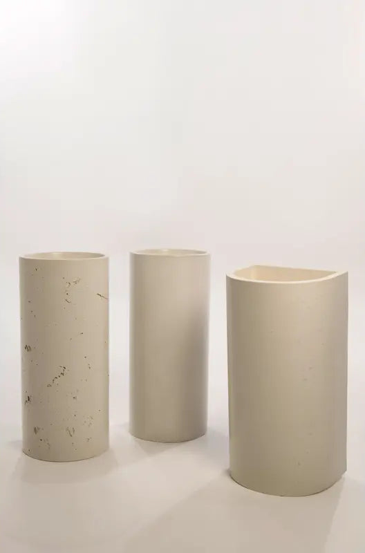 Three concrete basin designs featuring cylindrical and semi-circular cuts, showcasing smooth and textured finishes in neutral tones.